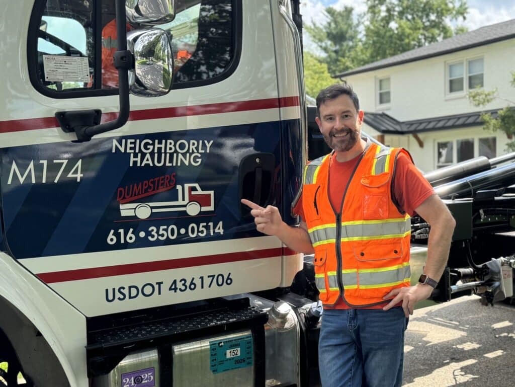 Justin Gray of Neighborly Hauling standing by Neighborly Hauling dumpster truck in Grand Rapids