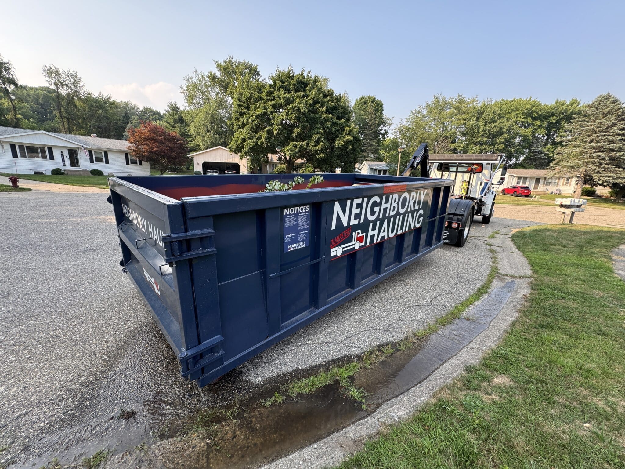 HDPE Rolliskate driveway protection boards placed under a Neighborly Hauling dumpster in a Grand Rapids residential driveway.